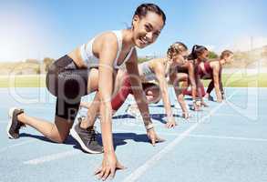 Portrait of female athlete motivated and ready to compete in track and field olympic event. Diverse group of competitive women with hands on the starting line ready to race and determined to win