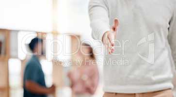 Businessperson extending their hand for a handshake in an office alone at work. One business professional giving a handshake and greeting. Employee welcoming you to the workplace