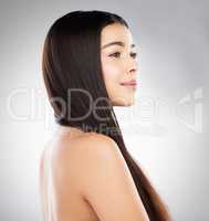 New hair, whos this. Studio shot of a beautiful young woman showing off her long silky hair against a grey background.