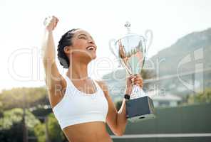 I earned this. a sporty young woman cheering while holding a trophy that she won in a tennis match.