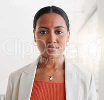 Young mixed race businesswoman standing alone in an office at work. Face of one confident hispanic businessperson looking serious standing at work