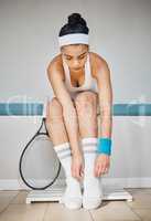 Stay ready, play steady. an attractive young woman tying her shoelaces in preparation for a game of tennis.
