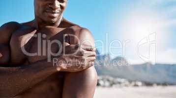 Closeup shot of an african american muscular athletic man holding his shoulder in pain. Black unrecognizable male suffering from arthritis in his arm. Suffering from a hurting, stiff, injured joint
