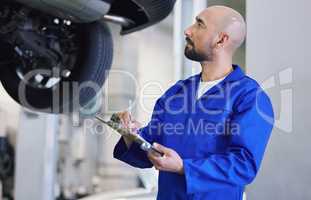 Putting your car to the test. a handsome young male mechanic working on the engine of a car during a service.