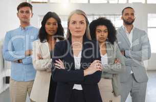 Group of diverse and powerful businesspeople standing together with their arms folded in an office. Confident and mature manager leading her team of professionals in the workplace. Global business