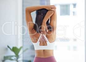 Stretch your body well so you can maintain flexibility. Rearview shot of a sporty young woman stretching her arms while exercising in a yoga studio.