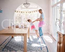 Celebrate and be your very happiest. Shot of an adorable little girl wearing a tutu and dancing with her father in the living room.