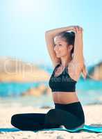 Beautiful woman practising yoga exercise on the beach. Young female athlete stretching while working out outside. Finding inner peace, balance and getting healthy. Focused on a fitness lifestyle