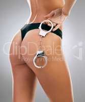 Cuff me Mr. Officer. an unrecognizable woman posing with handcuffs in her under against a grey background in studio.
