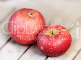 Two red apples on a wooden table indoors. Eat healthy and watch your diet. Fruit contains essential vitamins to boost your immunity. Closeup of a delicious snack vegans and vegetarians can enjoy