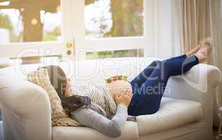 Relaxation is a must for a healthy pregnancy. an attractive young pregnant woman balancing wooden blocks on her tummy while relaxing on the sofa at home.
