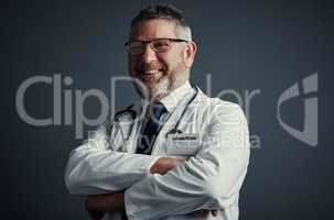 Allow me to give you a second opinion. Studio portrait of a handsome mature male doctor standing with his arms folded against a dark background.