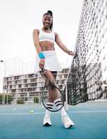 Smiling young girl ready for her tennis practice. African american tennis player standing on the court at her club. Happy woman holding her tennis racket at her club. Woman ready to compete in a match