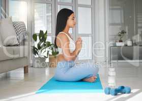 Meditate with mindful breathing. Shot of a sporty young woman meditating while practising yoga at home.