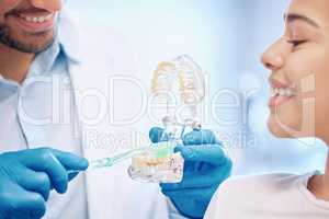 The best way to keep clean. a dentist demonstrating the best way to brush teeth to a patient.