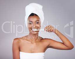 Im big on oral hygiene. Studio portrait of an attractive young woman brushing her teeth against a grey background.