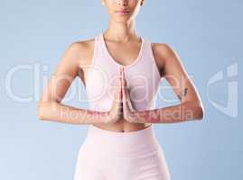 Closeup mixed race fitness woman meditating in studio against a blue background. Young hispanic female athlete with hands together for meditation. Focused on finding inner peace and balance
