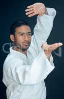 Come at me. a handsome young male martial artist practicing karate in studio against a dark background.