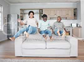 Rejoice with your family in the beautiful land of life. Shot of a family jumping on to the sofa at home.