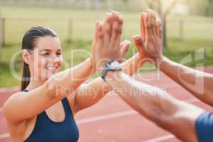 Lets do this. an attractive young female athlete high fiving an unrecognizable male teammate while standing out on the track.