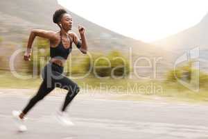 One african american female athlete looking focused while out for run to increase her cardio and endurance. A young black woman running outside to increase her speed and pace. Fitness is a lifestyle