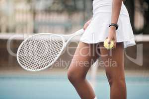 Closeup on the hands of a tennis player on the court. African american tennis player holding her ball and tennis racket on the court. Woman ready to compete in a tennis match at her club