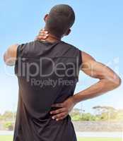 Rearview of athlete with neck pain. Closeup back view of an uncomfortable young sportsman standing on a sport field holding his stiff and inflamed joints. Muscle strain due to injury