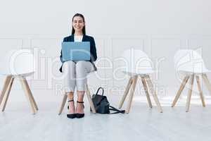 Full length portrait of one mixed race businesswoman sitting in a row and using her laptop to browse the internet while waiting for an interview. Hispanic candidate waiting in line for a job vacancy