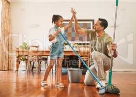 Adorable little girl helping her father sweep and mop wooden floors for household chores at home. Happy father and daughter doing spring cleaning together. Kid and parent high fiving while doing tasks