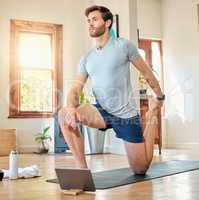 One fit young caucasian man stretching legs with lunge bodyweight exercise and holding foot while training with online tutorial on digital tablet at home. Guy gaining muscle, endurance, balance and core strength during yoga workout
