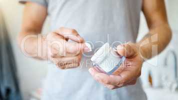 An unknown man applying cream or moisturiser to his face in a bathroom at home. One unrecognizable male using a lotion or sunscreen in his apartment