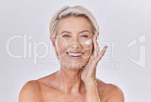 Portrait of one happy mature caucasian woman posing topless against a purple copyspace background. Ageing woman applying cream, moisturiser, sunblock during a skincare routine in a studio