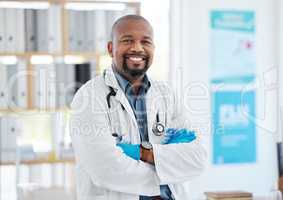 Proud confident young doctor in his office. African american doctor arms crossed in his hospital. Happy medical gp standing in his office. Medical specialist in his clinic office