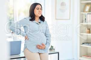 I need a moment to get through this pain. Shot of a pregnant businesswoman experiencing pain while working in an office.