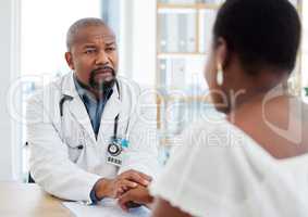Serious gp in a consult with a patient. African american doctor talking to a patient in a checkup. Woman getting support from her doctor during a checkup. Doctor holding a patients hand
