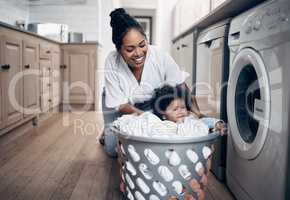 Who needs a nanny. a young mother playfully bonding with her baby girl while doing the laundry at home.