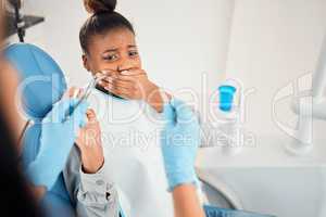 This is going to hurt. a young woman looking afraid at the dentists office.