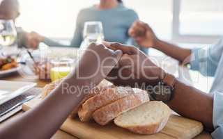 Bless this meal to our bodies oh God. Shot of two unrecognizable people holding hands at the dinner table at home.