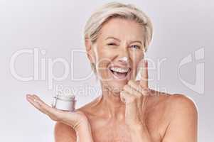 Portrait of one happy mature caucasian woman posing topless against a purple copyspace background. Ageing woman applying cream, moisturiser, sunblock during a skincare routine in a studio