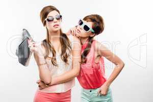 Twice as nice. Studio shot of two attractive young women dressed up in 60s wear against a white background.