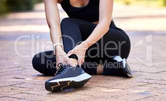 Closeup of one mixed race woman holding her sore ankle while exercising outdoors. Female athlete suffering with painful foot injury from fractured joint and inflamed muscles during workout. Struggling with stiff body cramps causing discomfort and strain