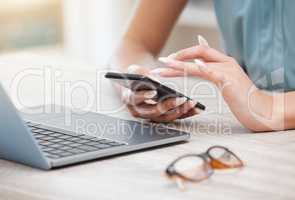 Closeup of females hands using smartphone while sitting at her desk. Business woman sitting by laptop and using mobile phone to send text, chatting on social network or browsing the internet