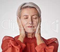 One mature woman suffering with a headache and looking stressed while posing against a grey copyspace background. Ageing woman experiencing anxiety and fear in a studio