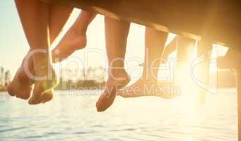 The still waters of a lake reflect the beauty around it. a group of friends sitting together on a pier.