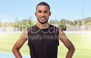 Portrait of a fit active young athlete standing alone before going for a run on a track field. Latino male looking confident and smiling outside getting ready to do his daily routine exercise outside