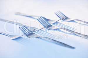 . Metal forks with shadows isolated on a white table.