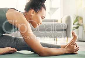 I get more out of my workout by stretching. Shot of a woman stretching on her exercise mat at home.