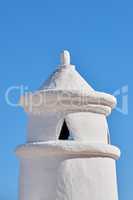 White chimney or bell tower designed on the roof of a house or building against a clear blue sky background with copyspace. Construction of exterior architectural structure at a historical monument