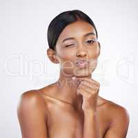 Wink wink. Studio portrait of an attractive young woman winking against a grey background.