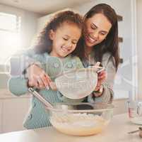 This is the secret to a light and fluffy cake. Shot of a mom baking with her daughter in their kitchen at home.